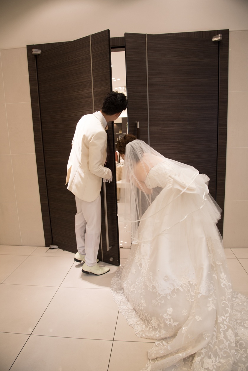 A Heart-Pounding Moment: The Adorable Snapshot of the Bride and Groom Peeking at Guests from Behind the Door!にて紹介している画像