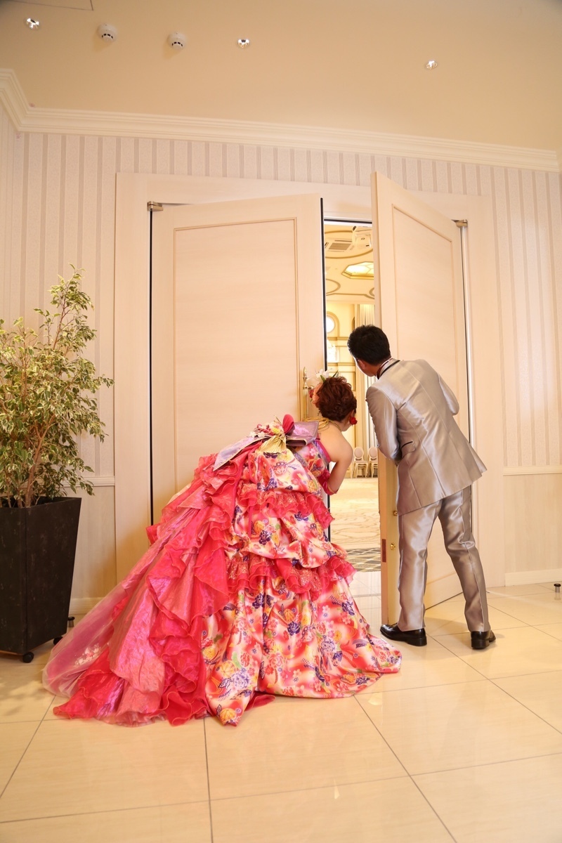 A Heart-Pounding Moment: The Adorable Snapshot of the Bride and Groom Peeking at Guests from Behind the Door!にて紹介している画像